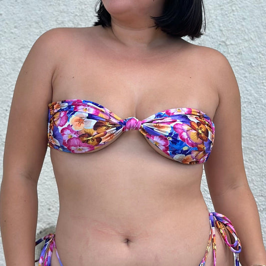 Person wearing a colorful bikini against a textured wall.