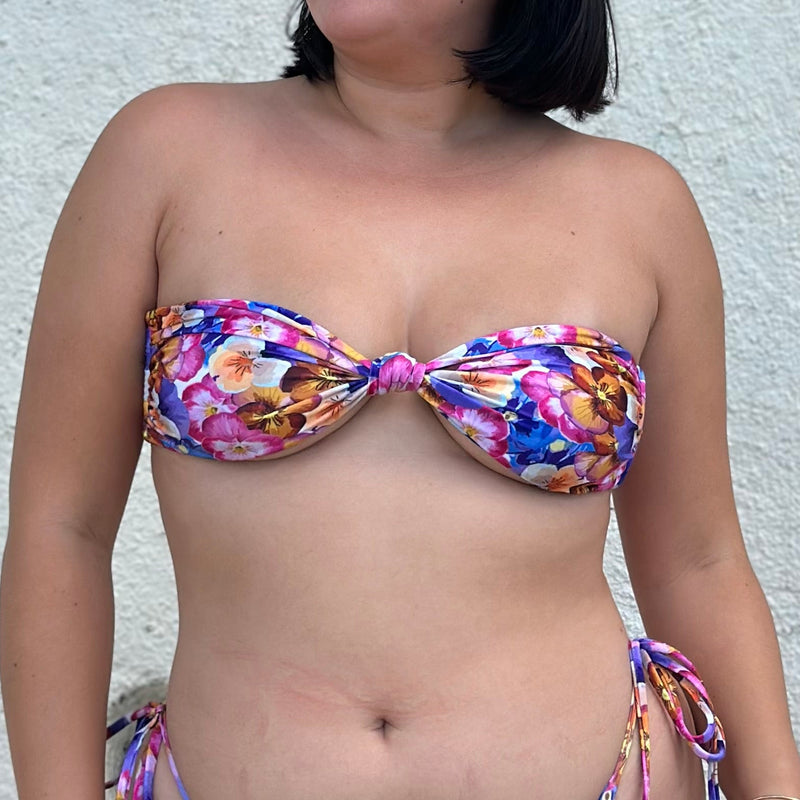 Person wearing a colorful bikini against a textured wall.